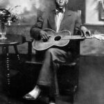 Charley Patton seated holding a Stella guitar in a Paramount publicity portrait circa 1929