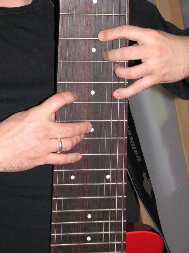 Both hands working on an electric guitar fretboard