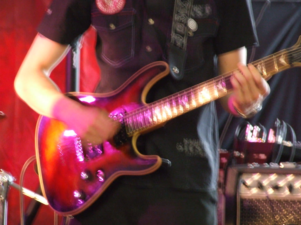 Live electric guitar stage mood. Not a Darwin named artist portrait. Photo nzgabriel. License CC BY 2.0.