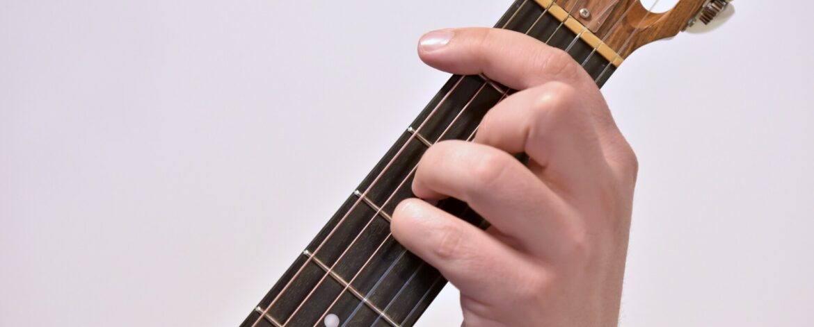 A hand holding an A sharp minor barre chord on a classical guitar neck, showing how to play barre chords