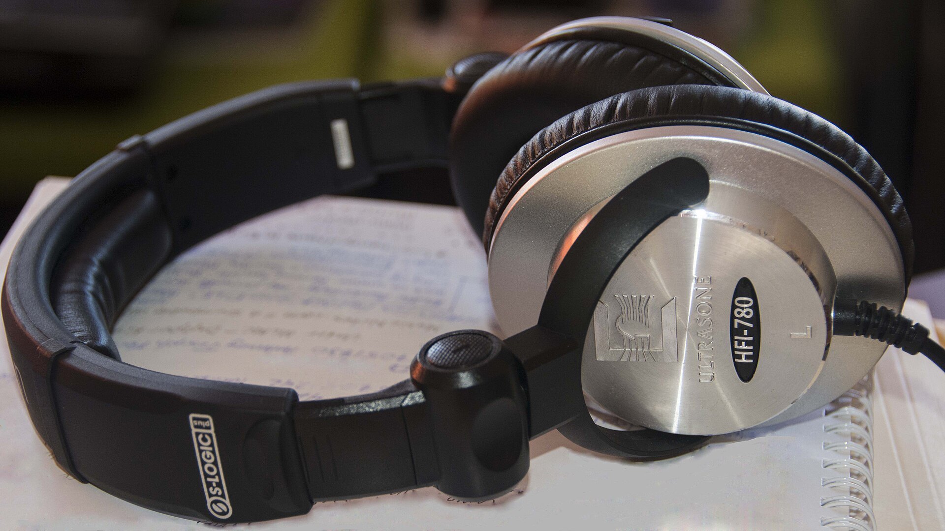Silver and black closed back studio headphones resting on sheets of paper, the kind used to monitor guitar while recording at home