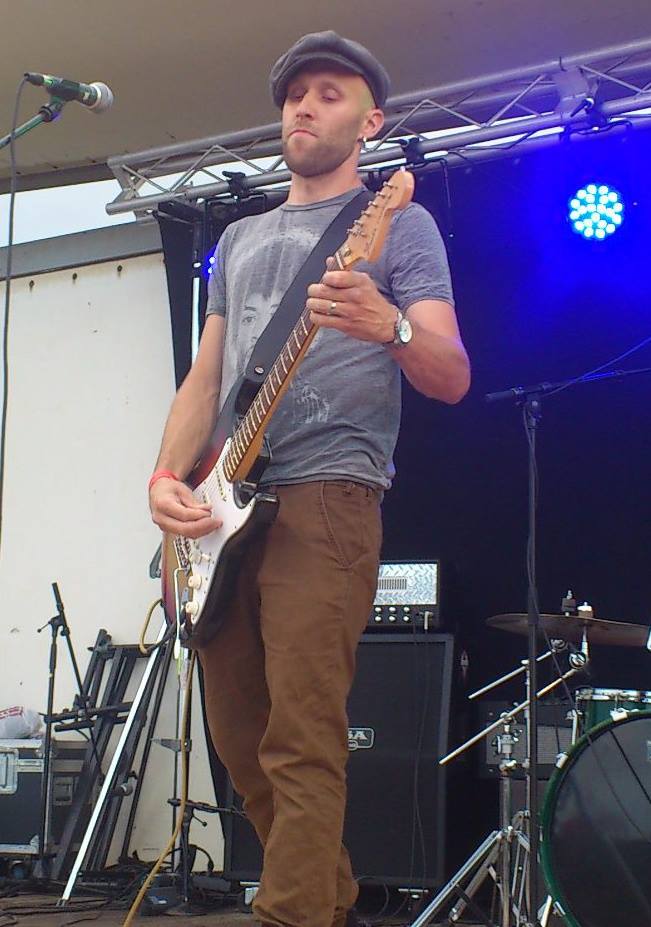 Guitarist performing a solo on an electric guitar on an outdoor stage
