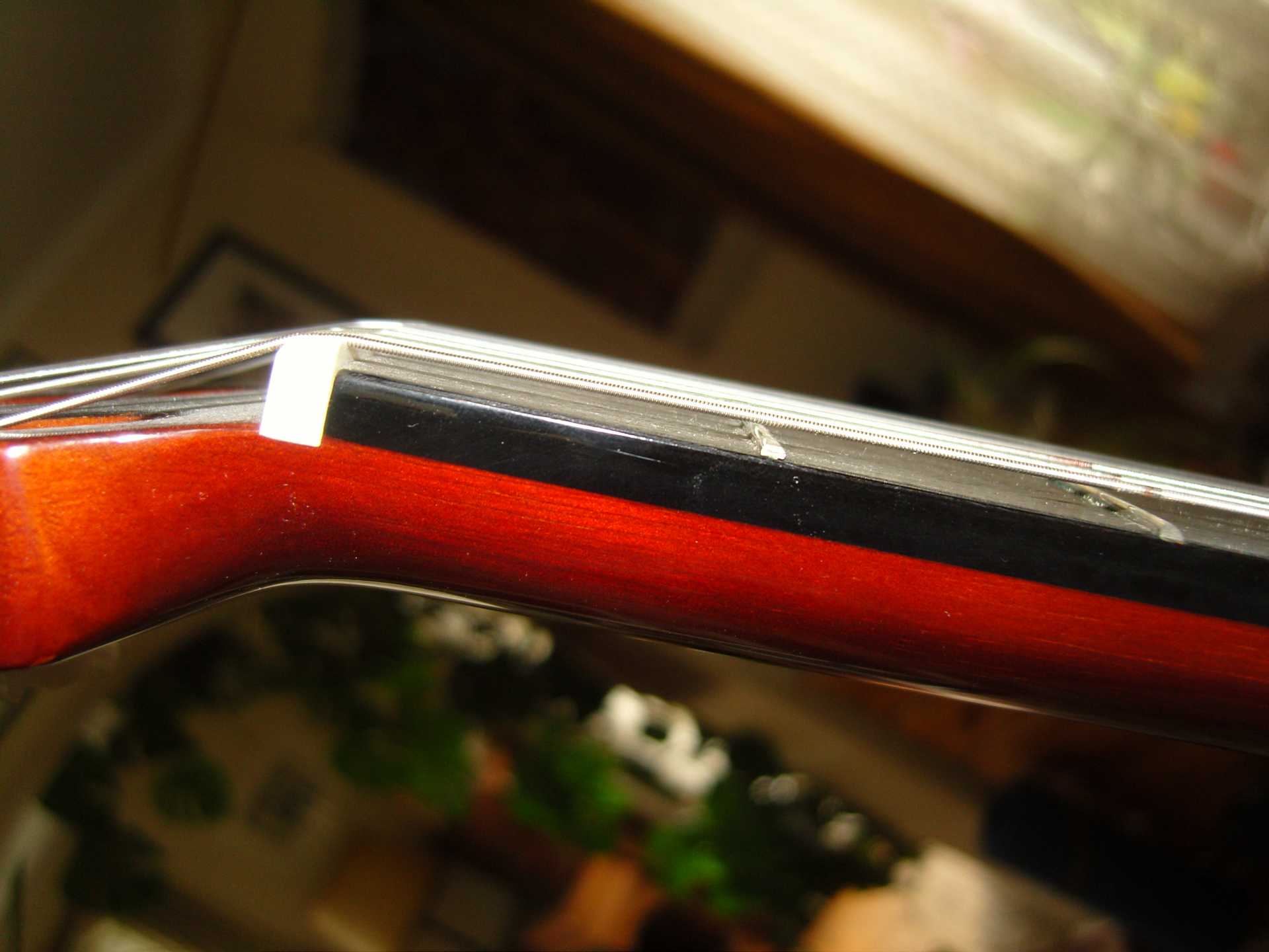 Side view of a classical guitar nut with the strings sitting high above the first frets