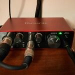 Home recording setup for guitar: a red Focusrite Scarlett Solo (3rd Gen) audio interface on a desk with an XLR lead and a guitar lead plugged in
