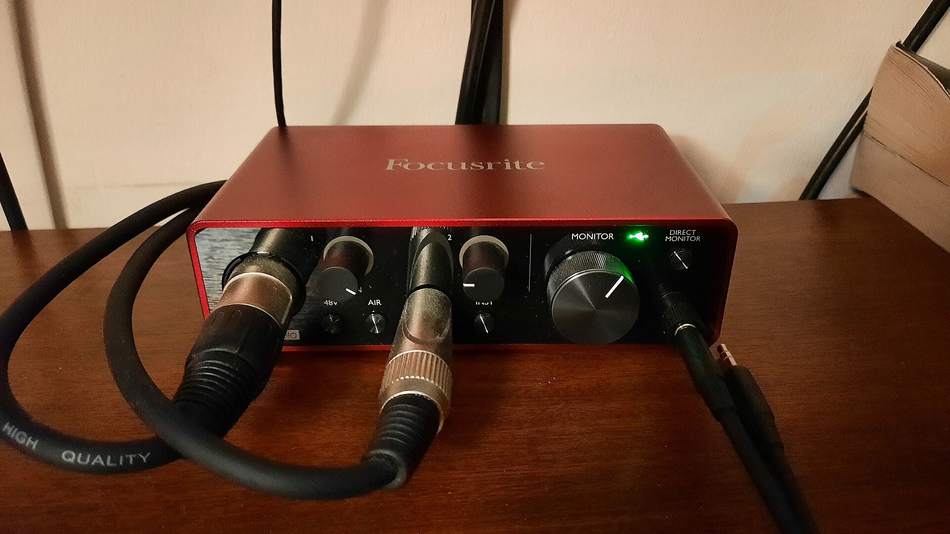 Home recording setup for guitar: a red Focusrite Scarlett Solo (3rd Gen) audio interface on a desk with an XLR lead and a guitar lead plugged in