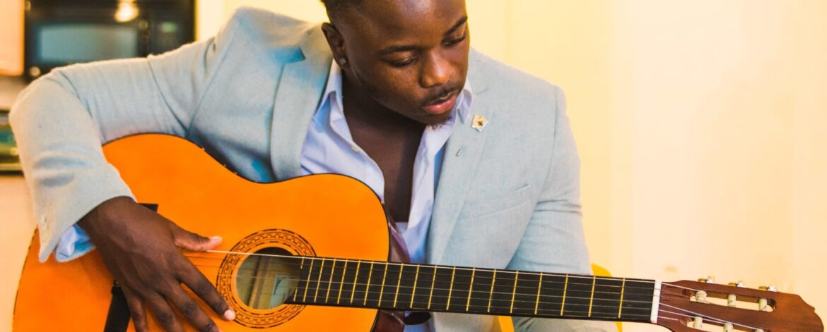 man_tuning_acoustic_guitar_by_ear Guitarist turning a tuning peg while listening closely, showing how to tune a guitar by ear and guitar tuning by ear without a tuner