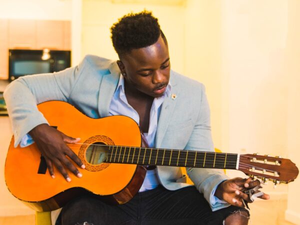 Guitarist turning a tuning peg while listening closely, showing how to tune a guitar by ear and guitar tuning by ear without a tuner
