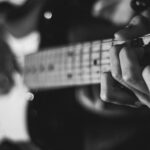 Guitarist fretting a chord, the first step in learning songs with common chord progressions by ear